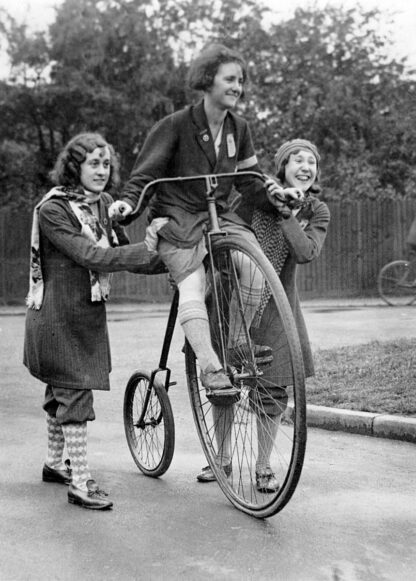 Girls attempting to ride penny farthing