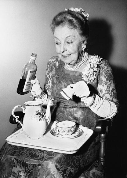 Lady adding gin to her tea